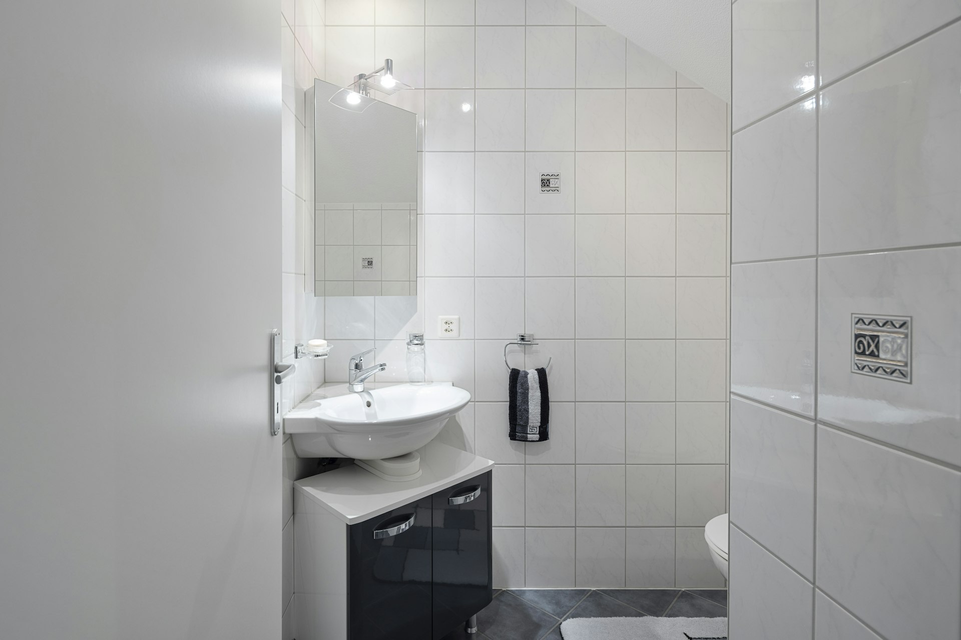 Kleines weißes Badezimmer mit Waschtisch und WC