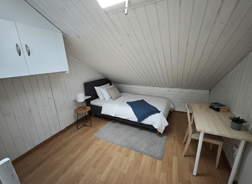 Dachzimmer mit Bett und Schreibtisch