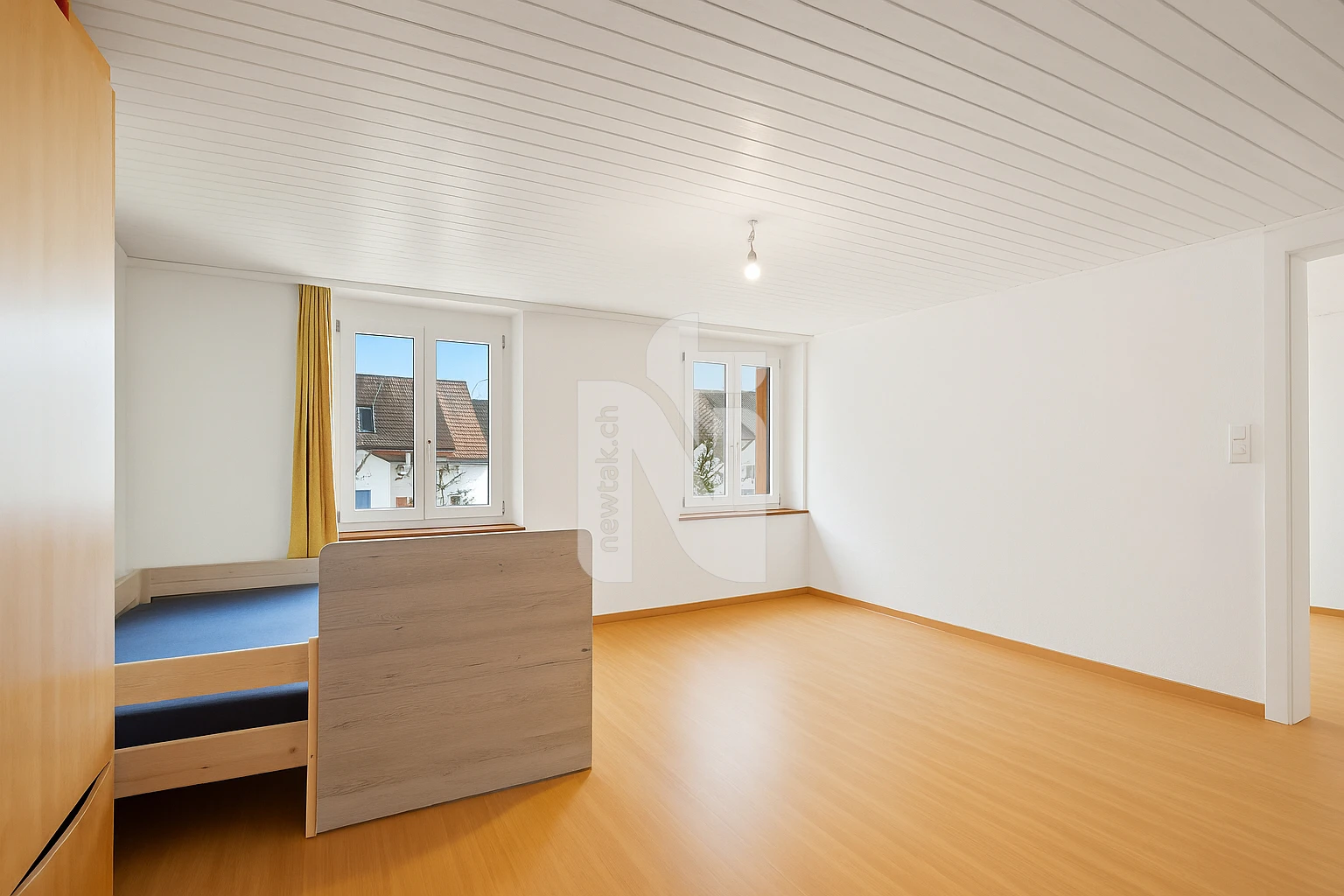Helles Schlafzimmer mit Dachschräge und zwei Fenstern