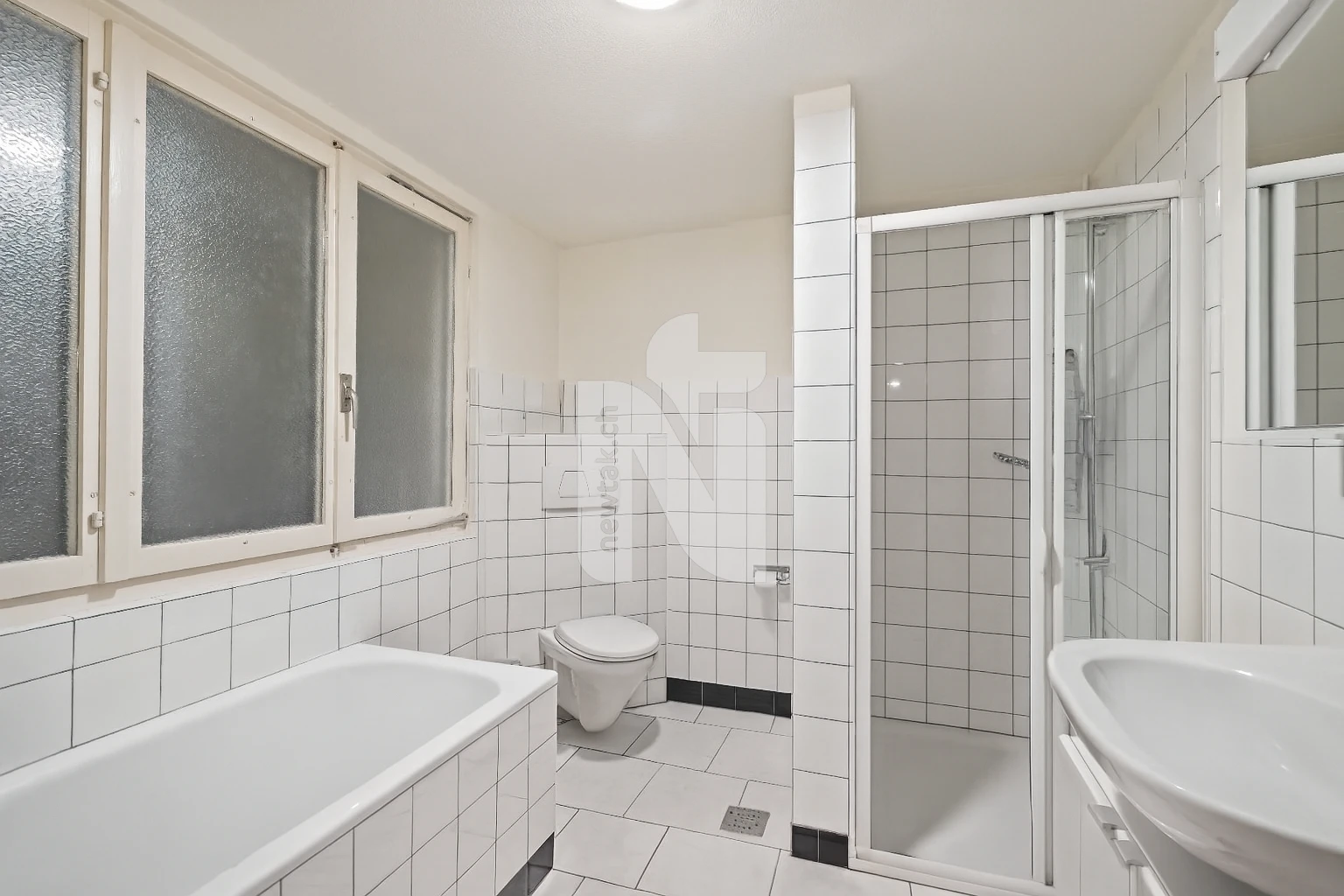 Kleines weiß gefliestes Badezimmer mit Badewanne und Dusche