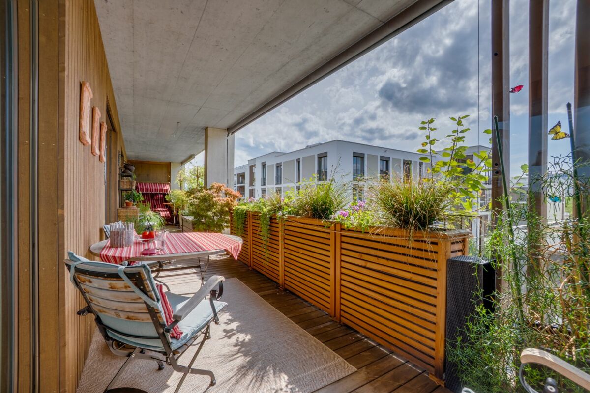 Überdachte Balkonterrasse mit Pflanzen und Sitzbereich