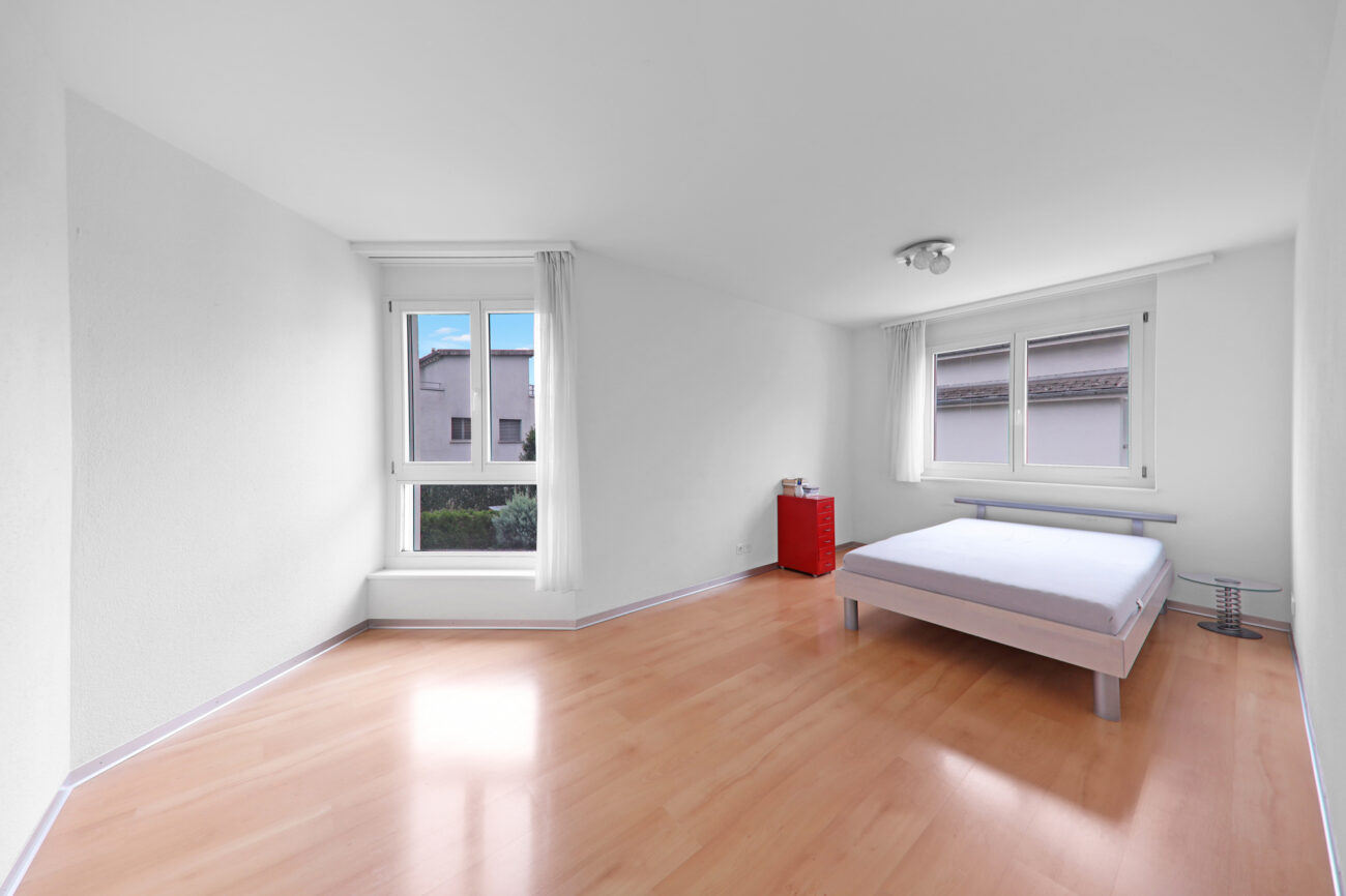 Helles Schlafzimmer mit Dachschrägen und zwei Fenstern