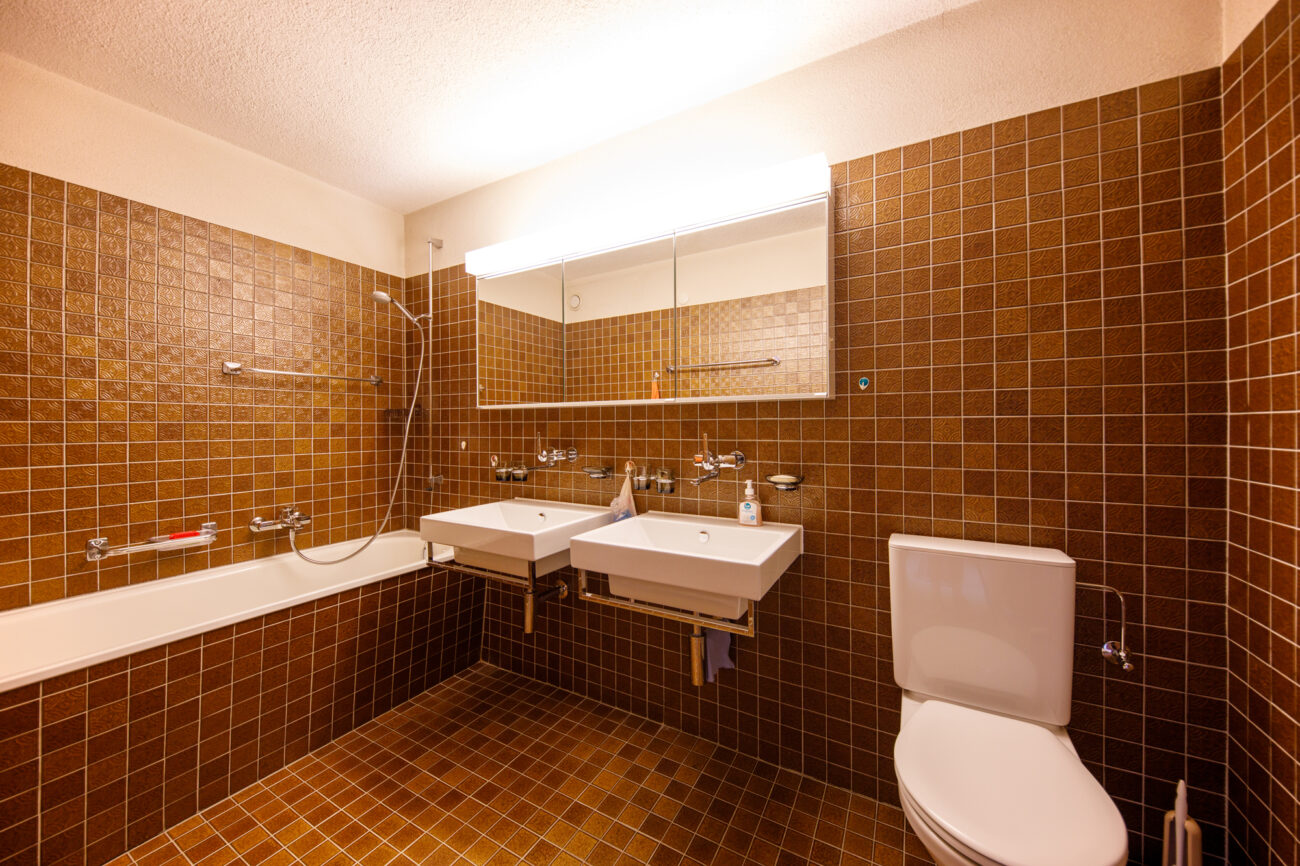 Braunes Badezimmer mit Wanne, Doppelwaschbecken und WC