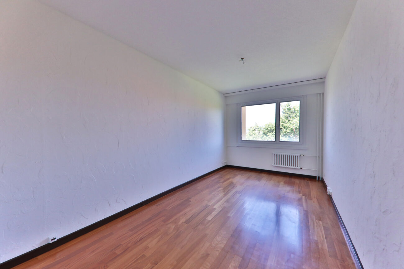 Leerer, heller Wohnraum mit Parkett und Fenster