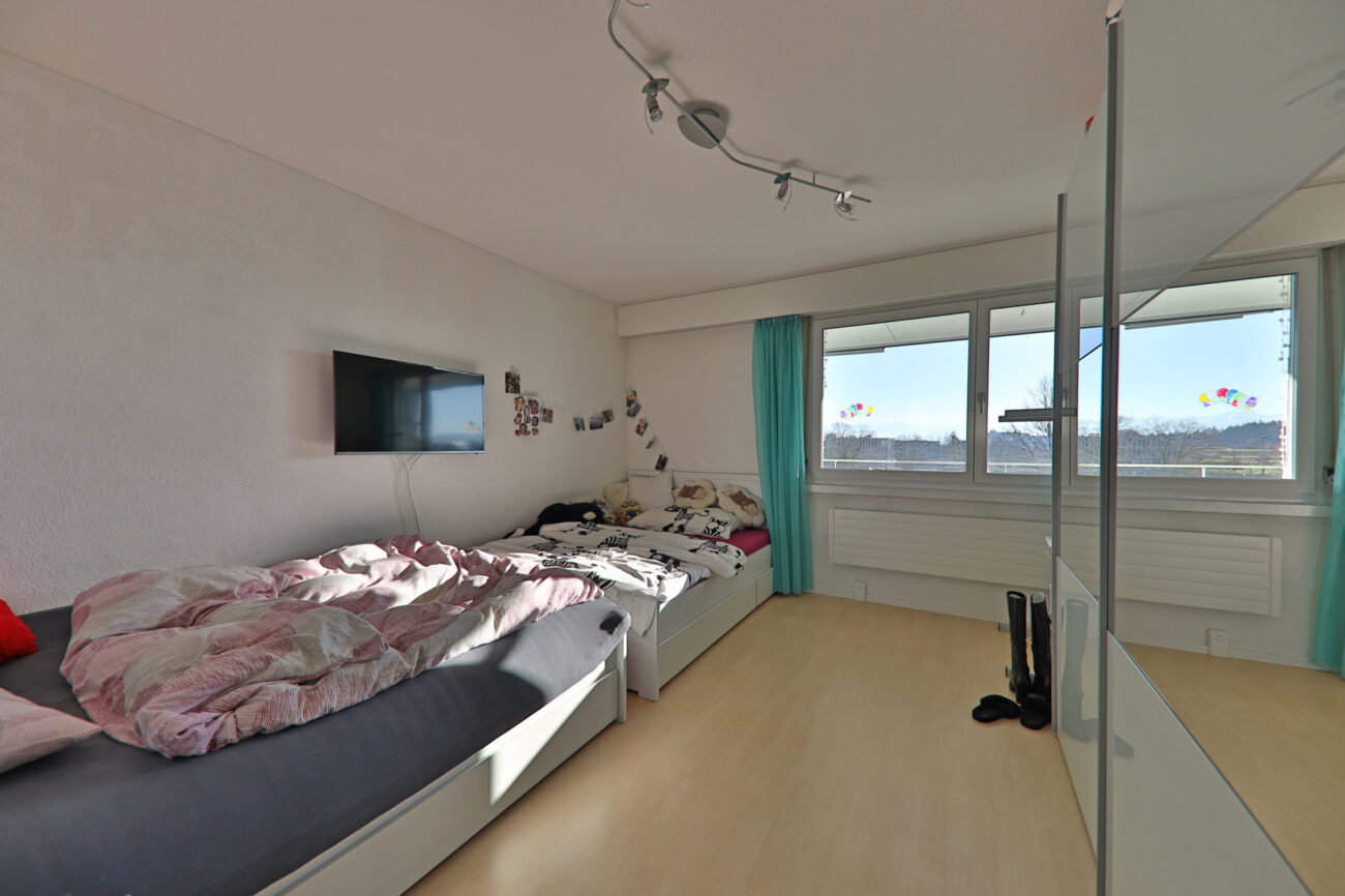 Helles Schlafzimmer mit zwei Einzelbetten und Balkonblick