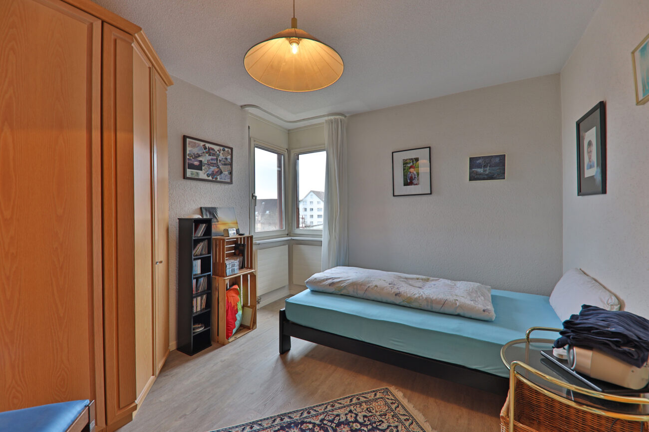 Helles Schlafzimmer mit Eckfenster und Holzschrank
