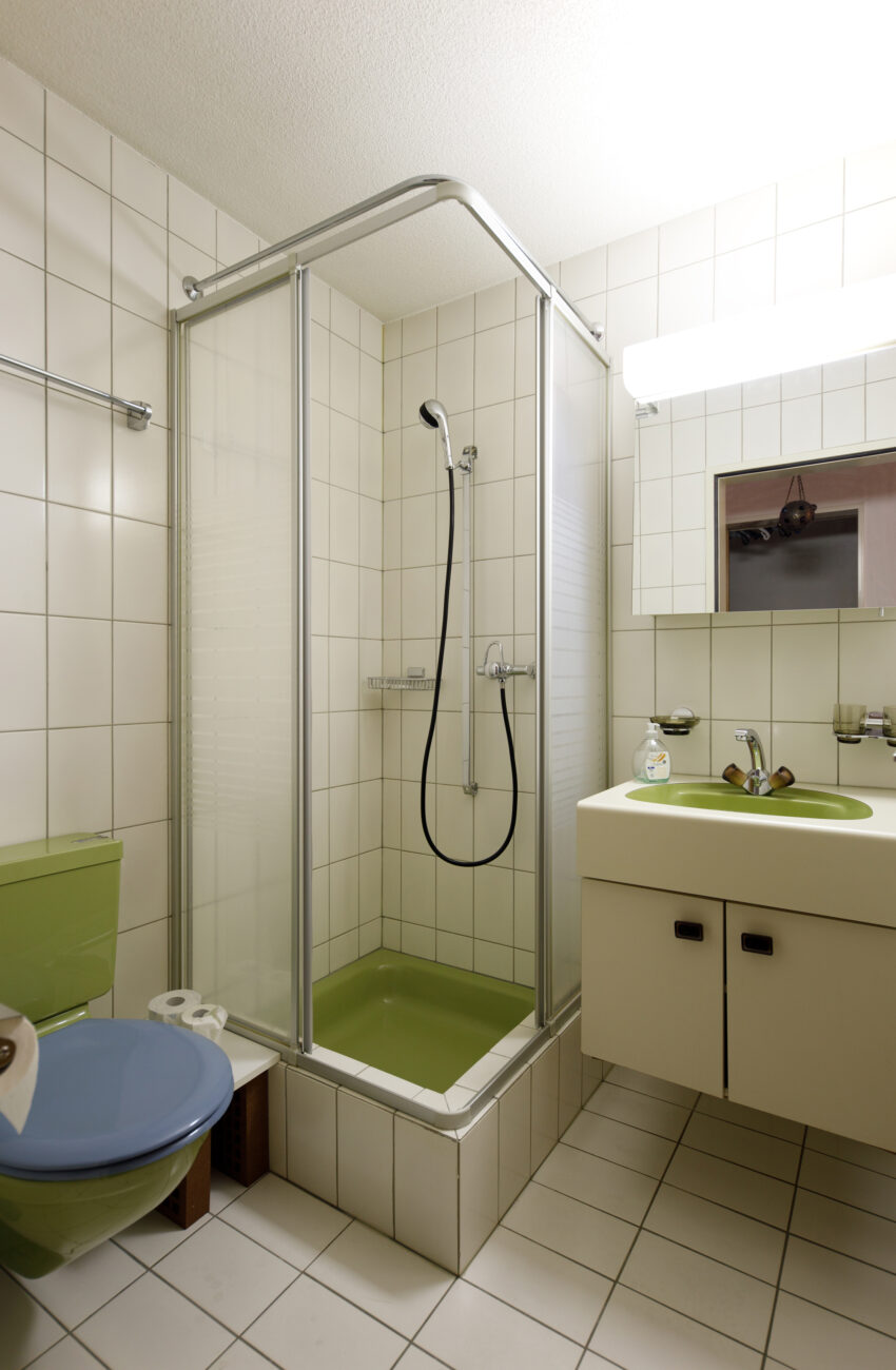 Kleines Badezimmer mit Dusche und grünem Waschbecken