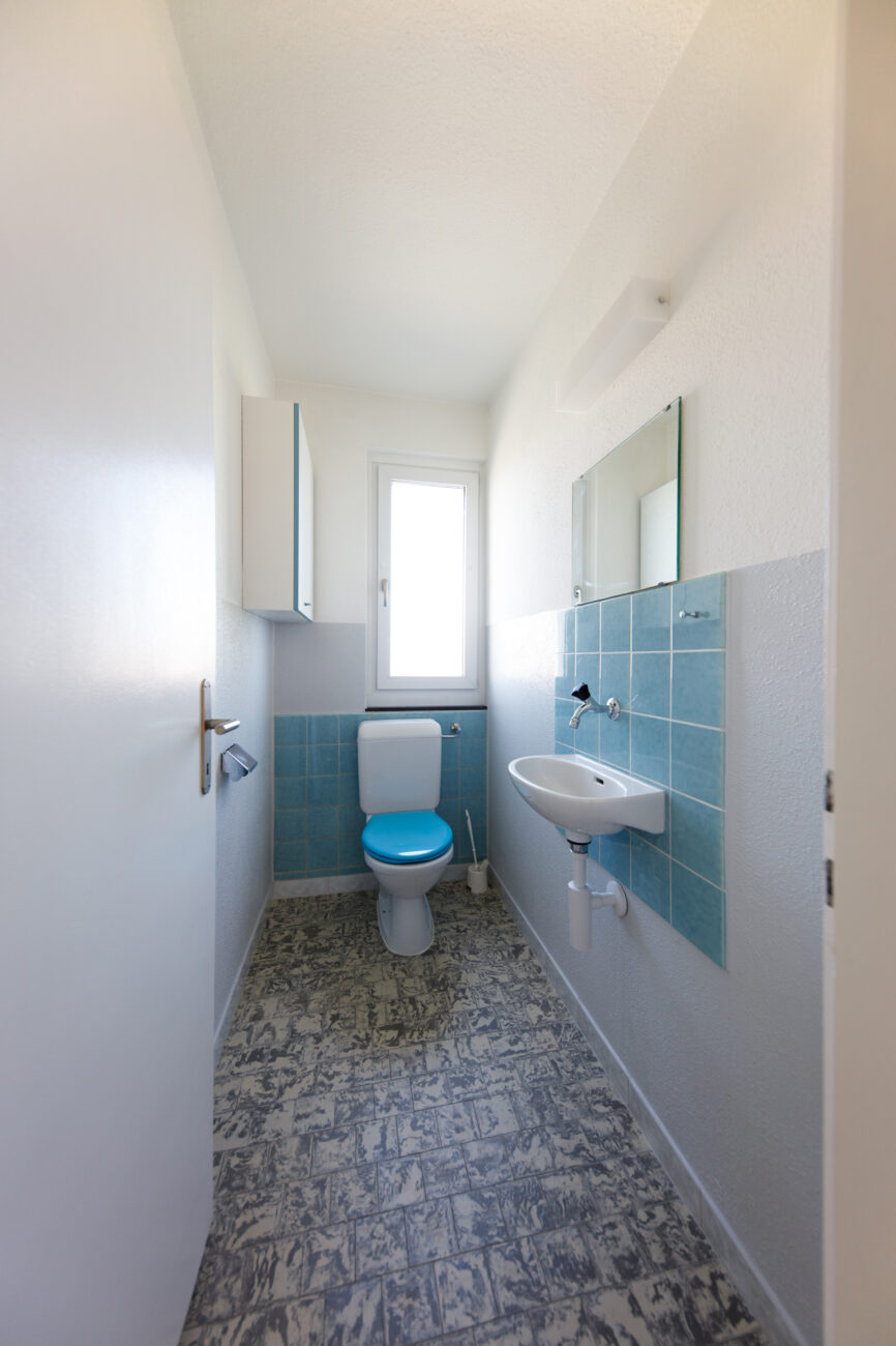 Kleines Gäste-WC mit blau gefliester Wandzone