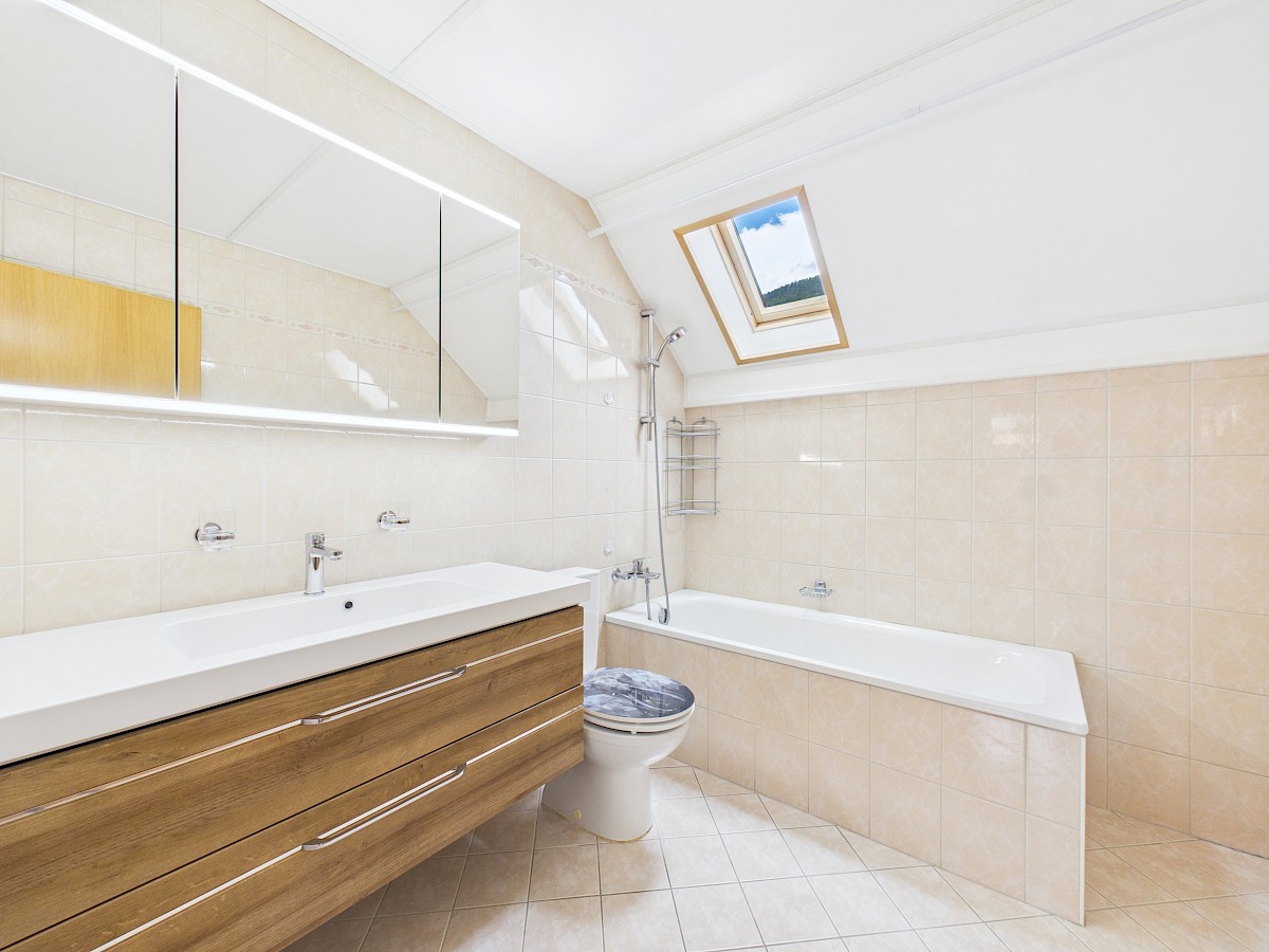 Helles Dachgeschossbad mit Badewanne und Spiegelschrank