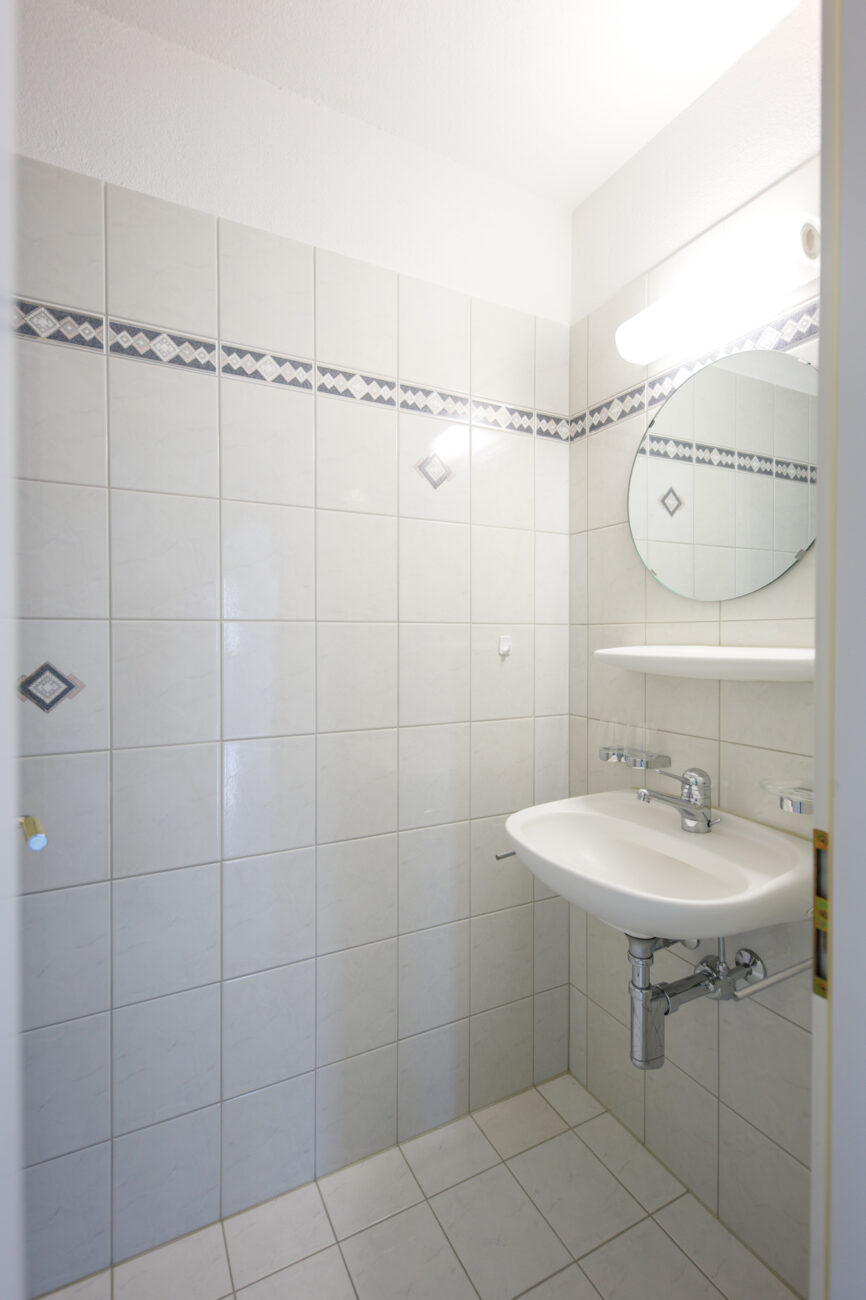 Kleines weiß gefliestes Bad mit Waschbecken