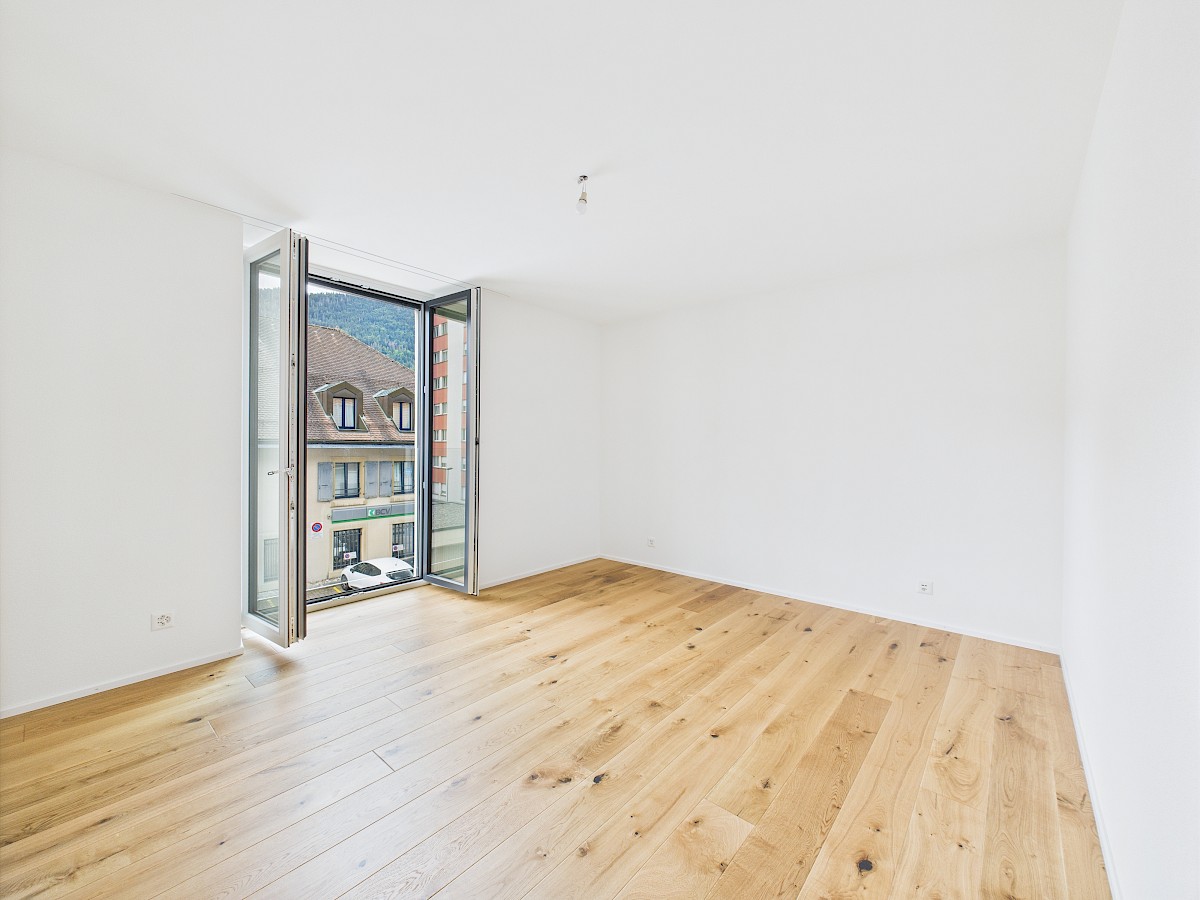 Helles, leeres Zimmer mit offenem Fenster und Parkett