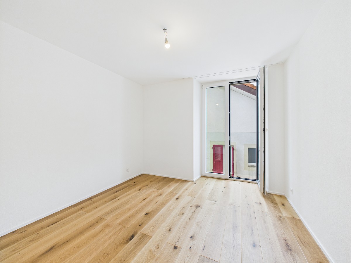 Heller leerer Raum mit Holzboden und Fenstertür