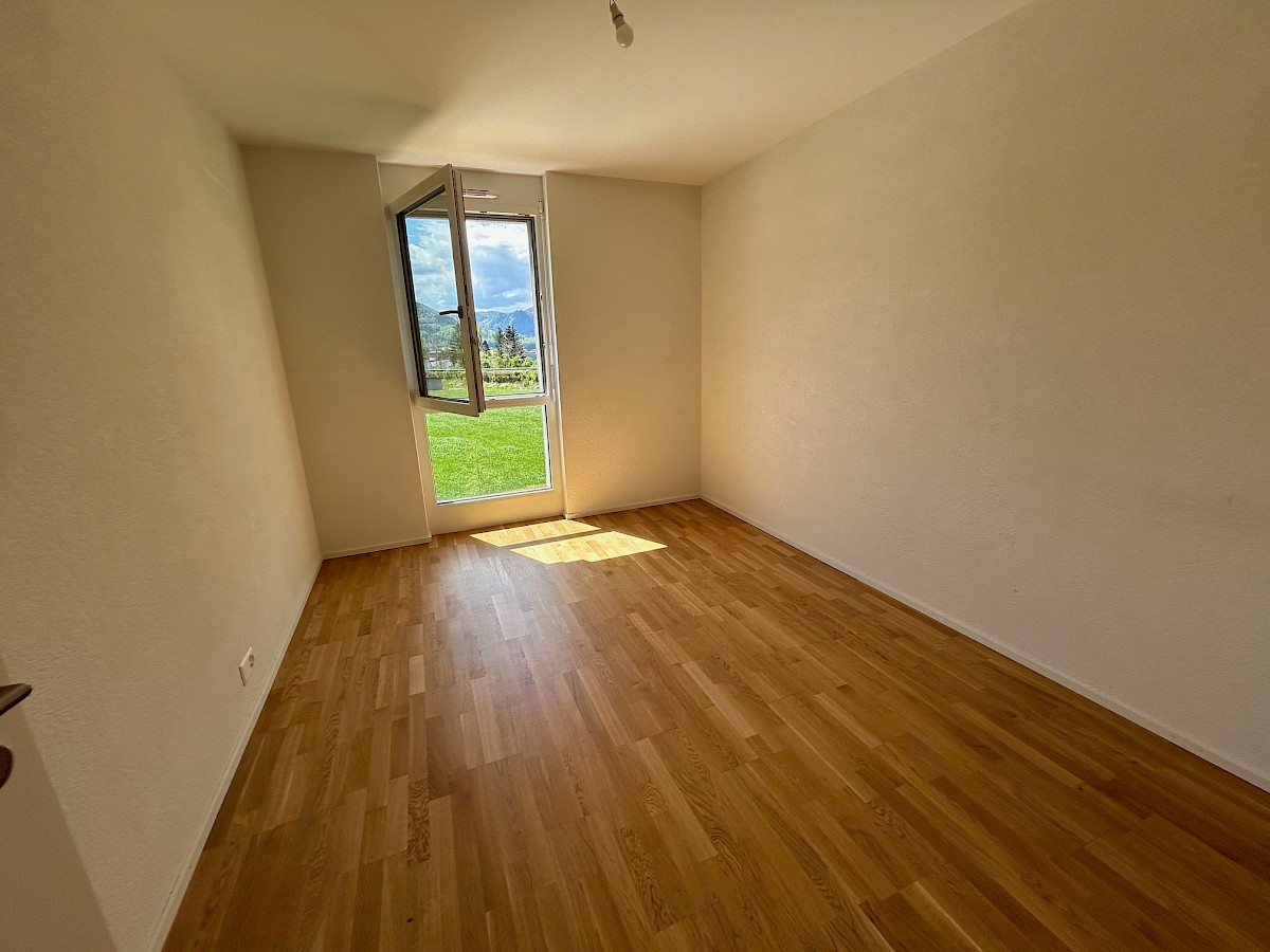 Heller leerer Raum mit Fensterblick auf Grün und Berge