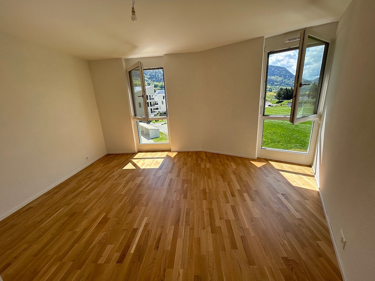 Heller, leerer Wohnraum mit großen Fenstern und Bergblick