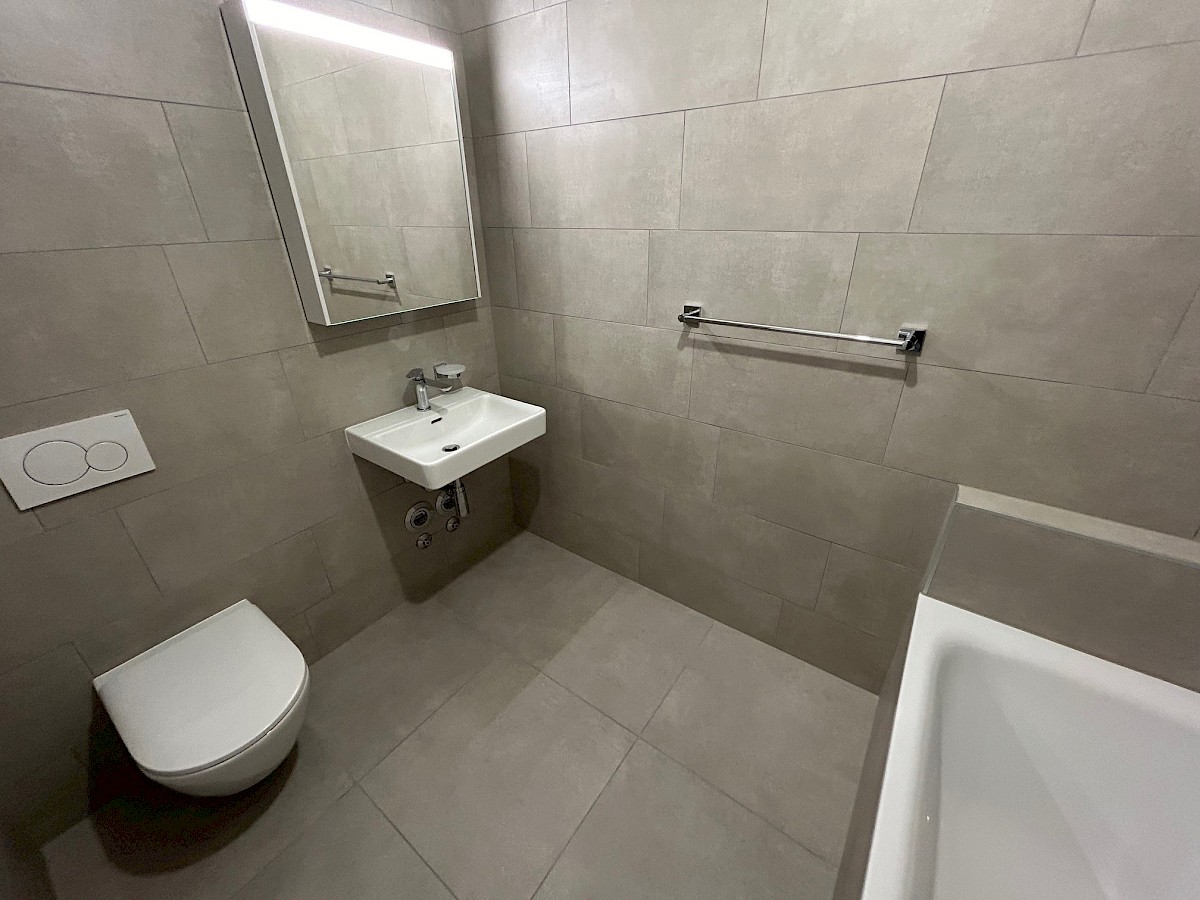 Modernes Badezimmer mit Wand-WC und Badewanne