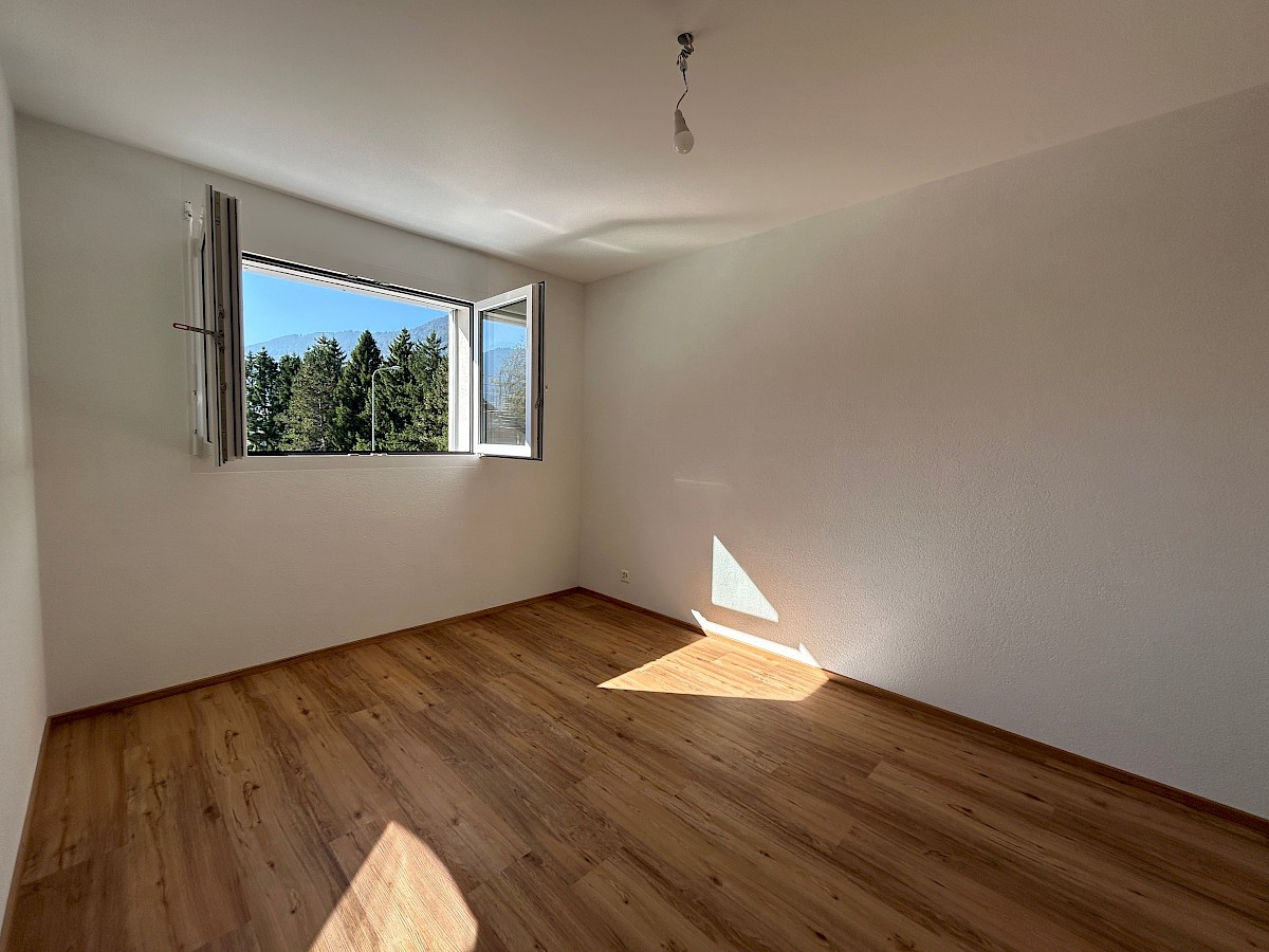 Leerer, heller Raum mit Holzfußboden und Fensterblick
