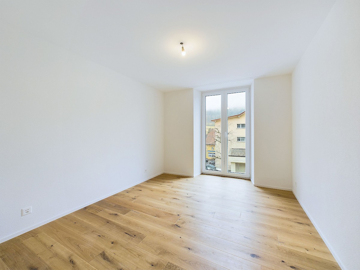 Heller leerer Raum mit Holzdielen und großem Fenster