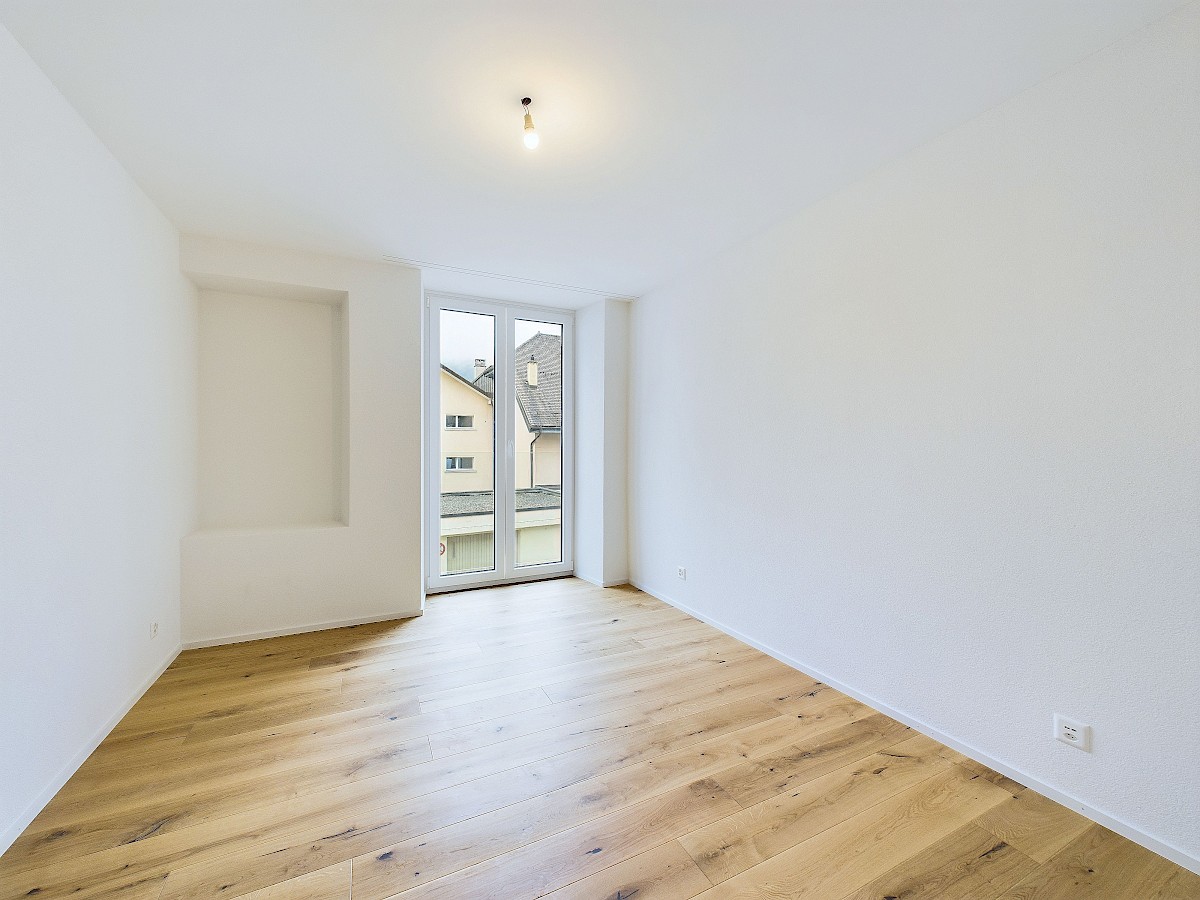 Leerer heller Raum mit Holzboden und Balkonfenster
