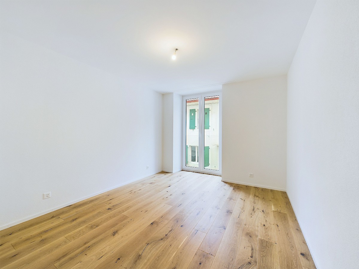 Heller leerer Raum mit Holzboden und Balkonfenster