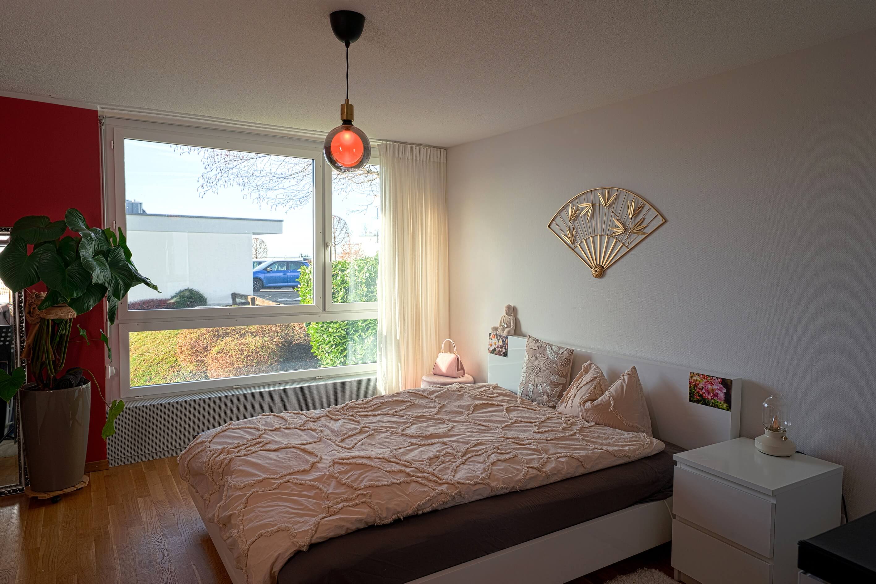 Schlafzimmer mit großem Fenster und Dekor in Rosa/Weiß
