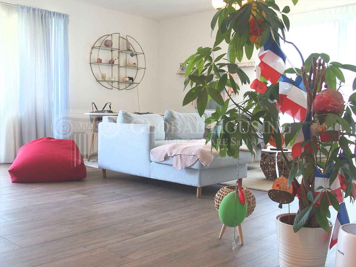 Hell eingerichtetes Wohnzimmer mit Pflanzen und hellem Sofa