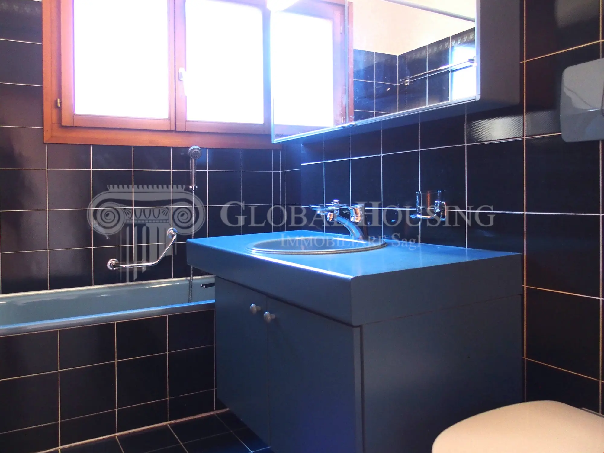Dunkles Badezimmer mit Waschbecken und Badewanne