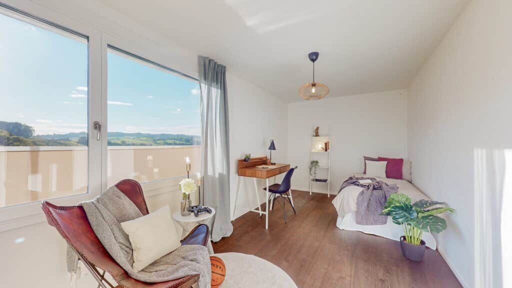 Helles Schlafzimmer mit Schreibtisch und Balkonblick