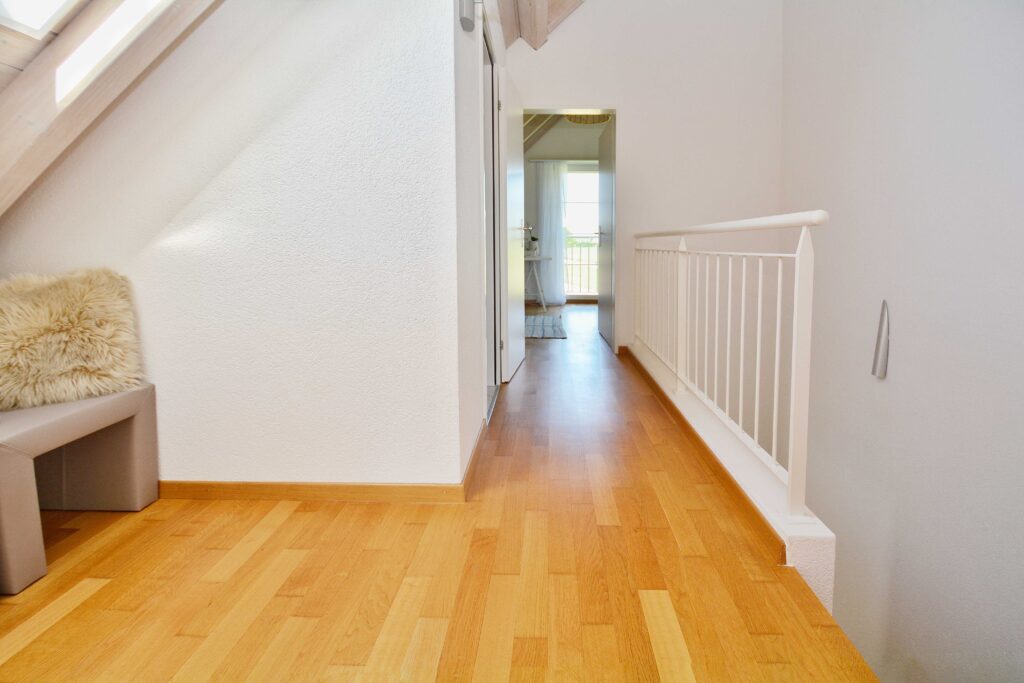 Heller Flur mit Holztreppe und Geländer
