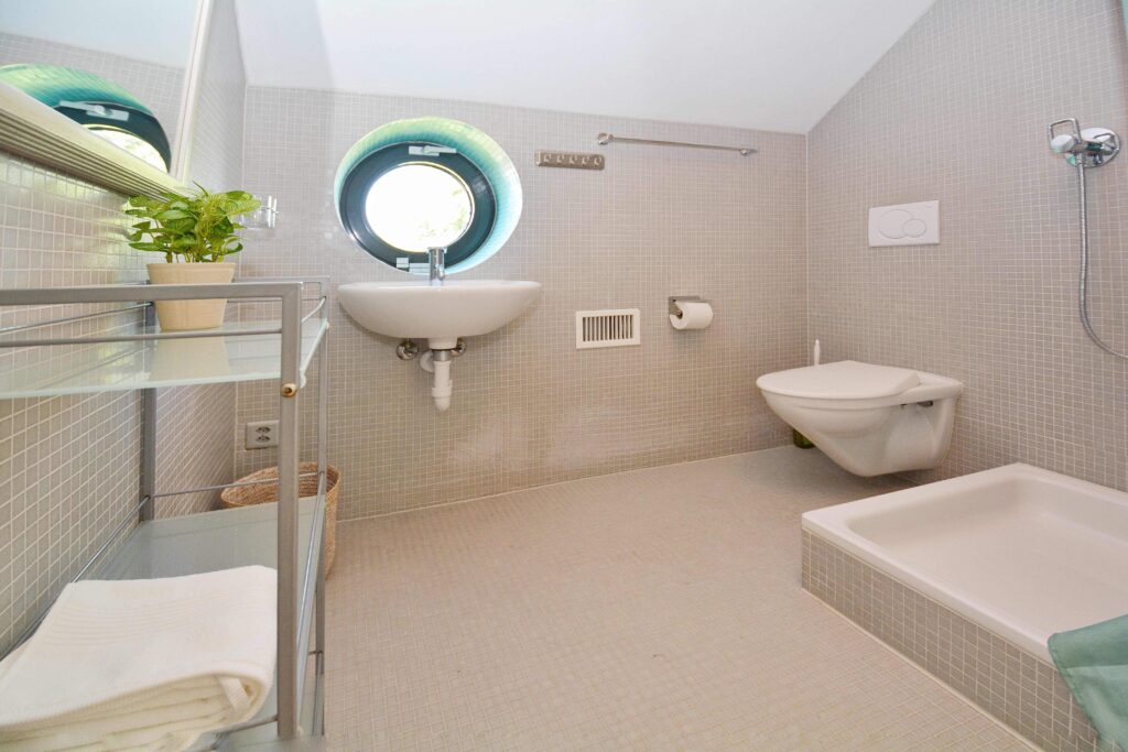 Modernes Badezimmer mit runder Fensteröffnung und Badewanne