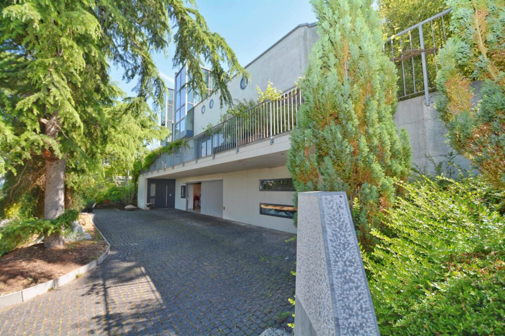 Moderne Außenansicht eines Hauses mit Zufahrt und viel Grün
