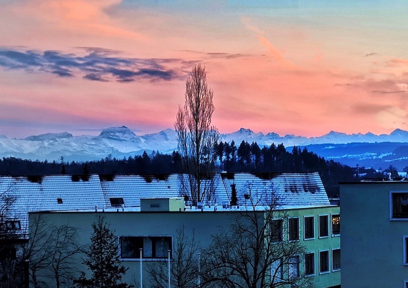 Blick über Dächer auf Gebirge bei Sonnenuntergang