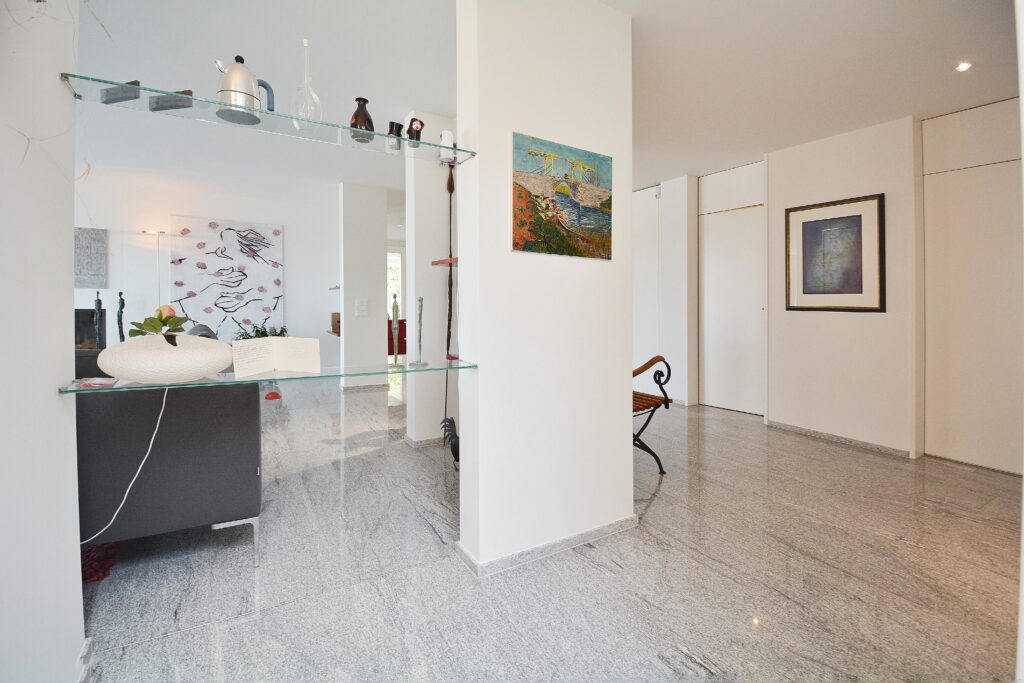 Heller Eingangsbereich mit Glasregal und Kunst