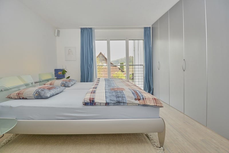 Helles Schlafzimmer mit Doppelbett und Balkonblick