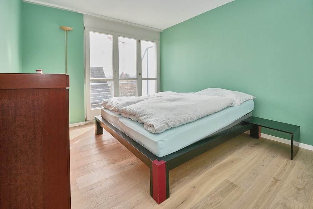 Helles Schlafzimmer mit Doppelbett und mintgrünen Wänden