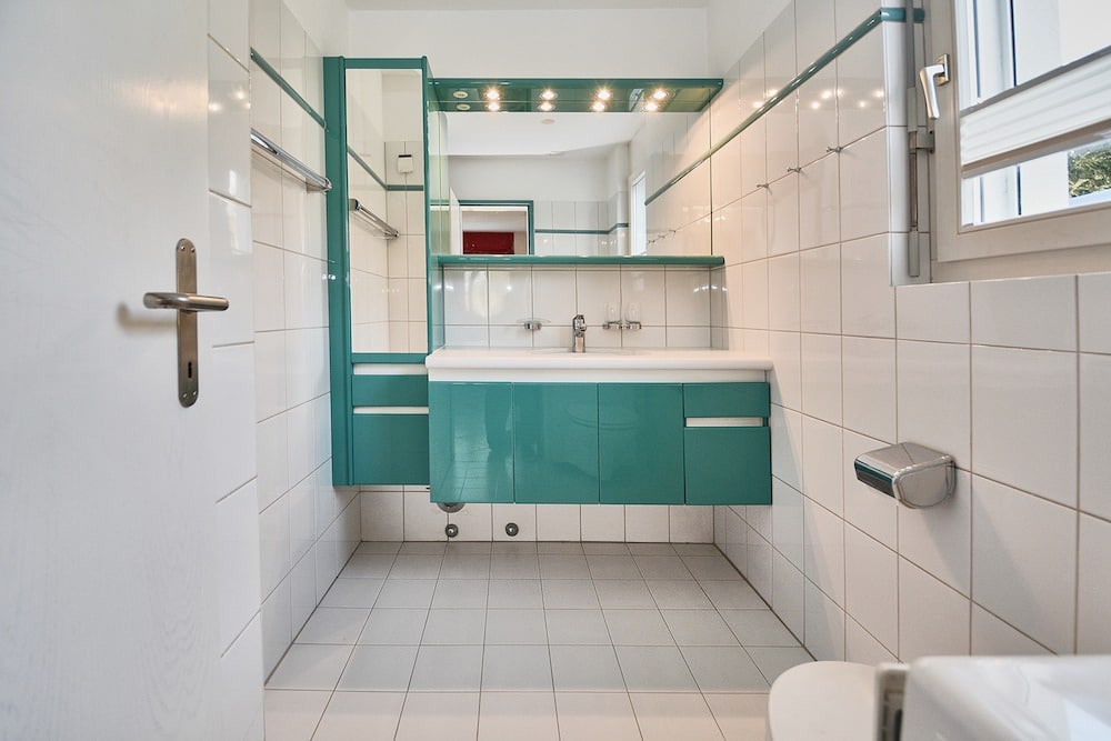 Modernes Badezimmer mit türkisfarbenen Möbeln und weißen Fliesen