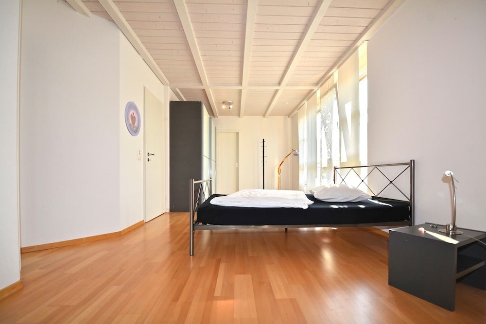 Helles Schlafzimmer mit Holzboden und sichtbaren Dachbalken