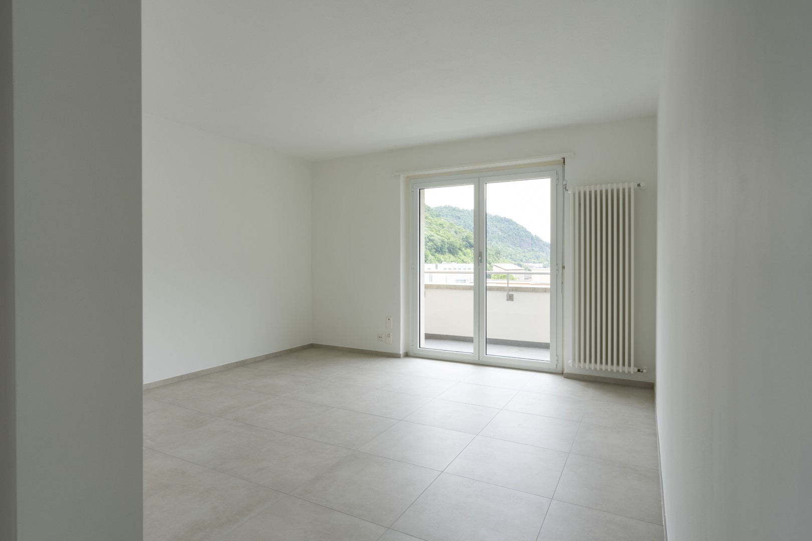 Leerer, heller Wohnraum mit Balkon und Bergblick