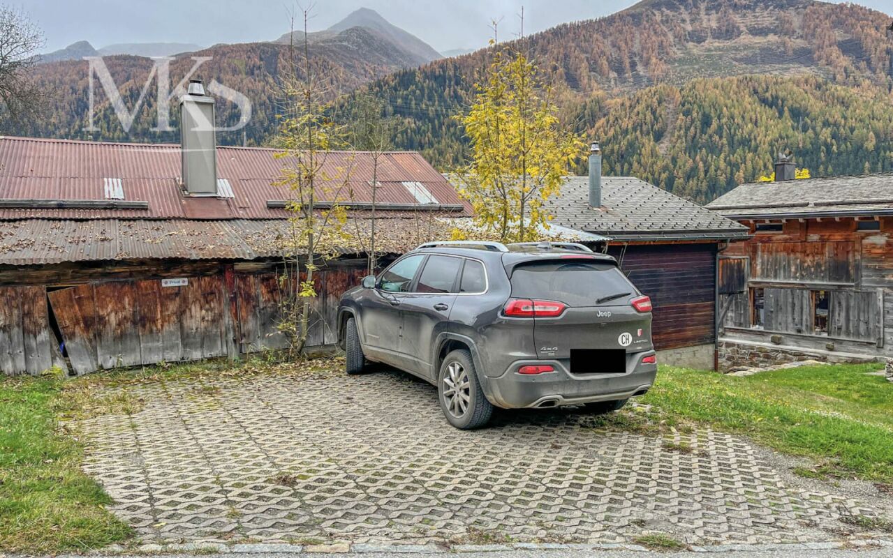 Alpinischer Hof mit Parkplatz und Bergkulisse