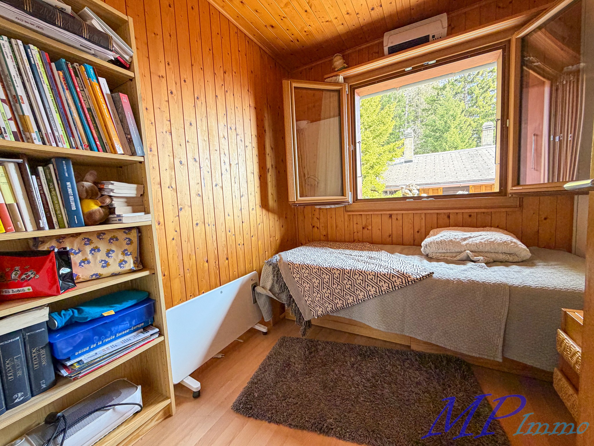Kleines Holzschlafzimmer mit offenem Fenster