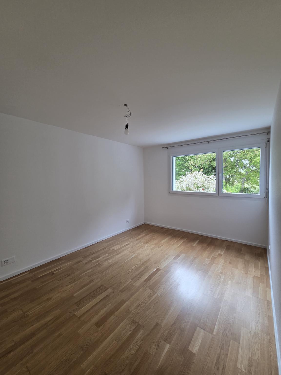 Leeres, helles Zimmer mit Holzfußboden