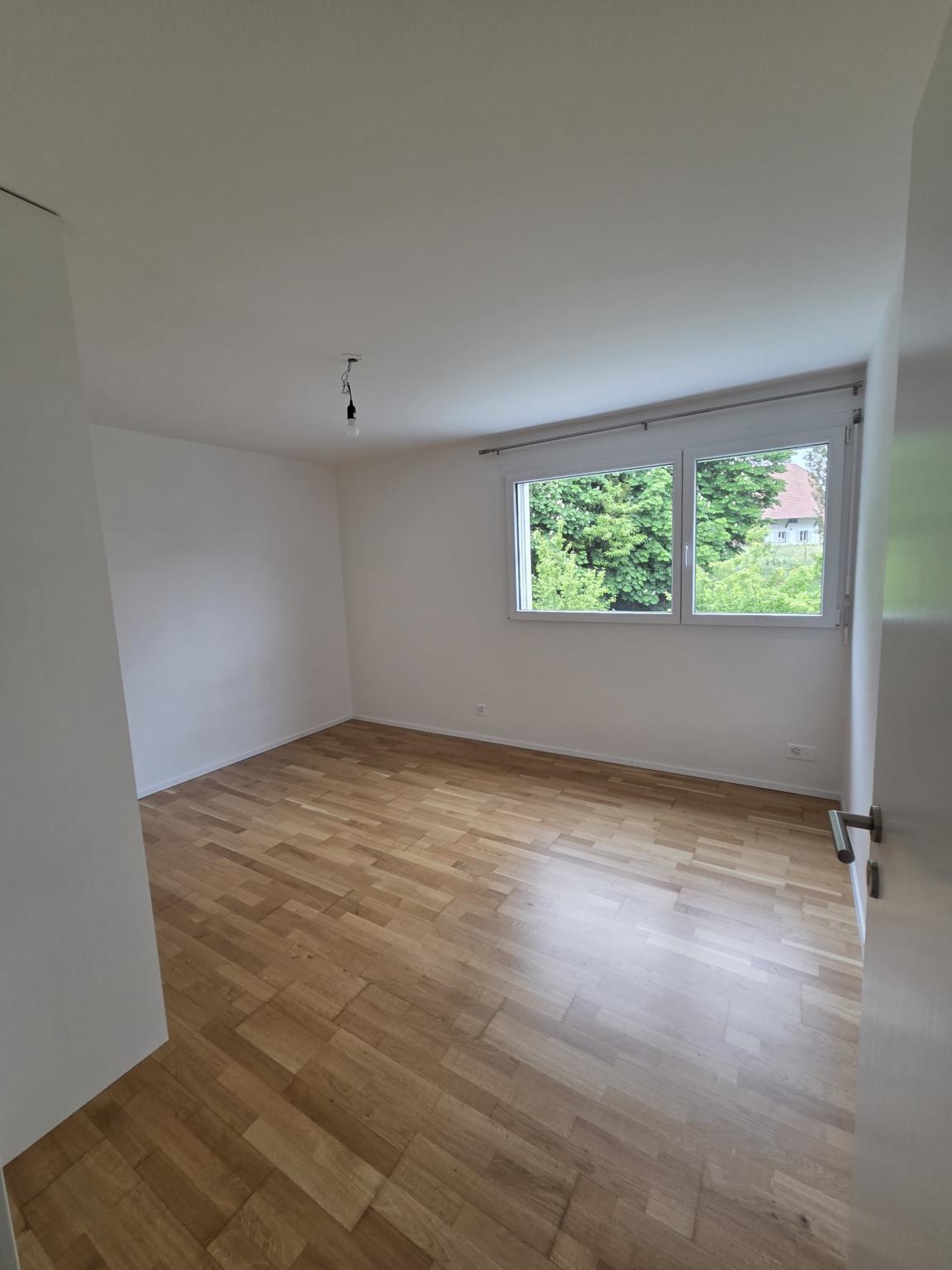 Heller leerer Raum mit Parkett und Fenster