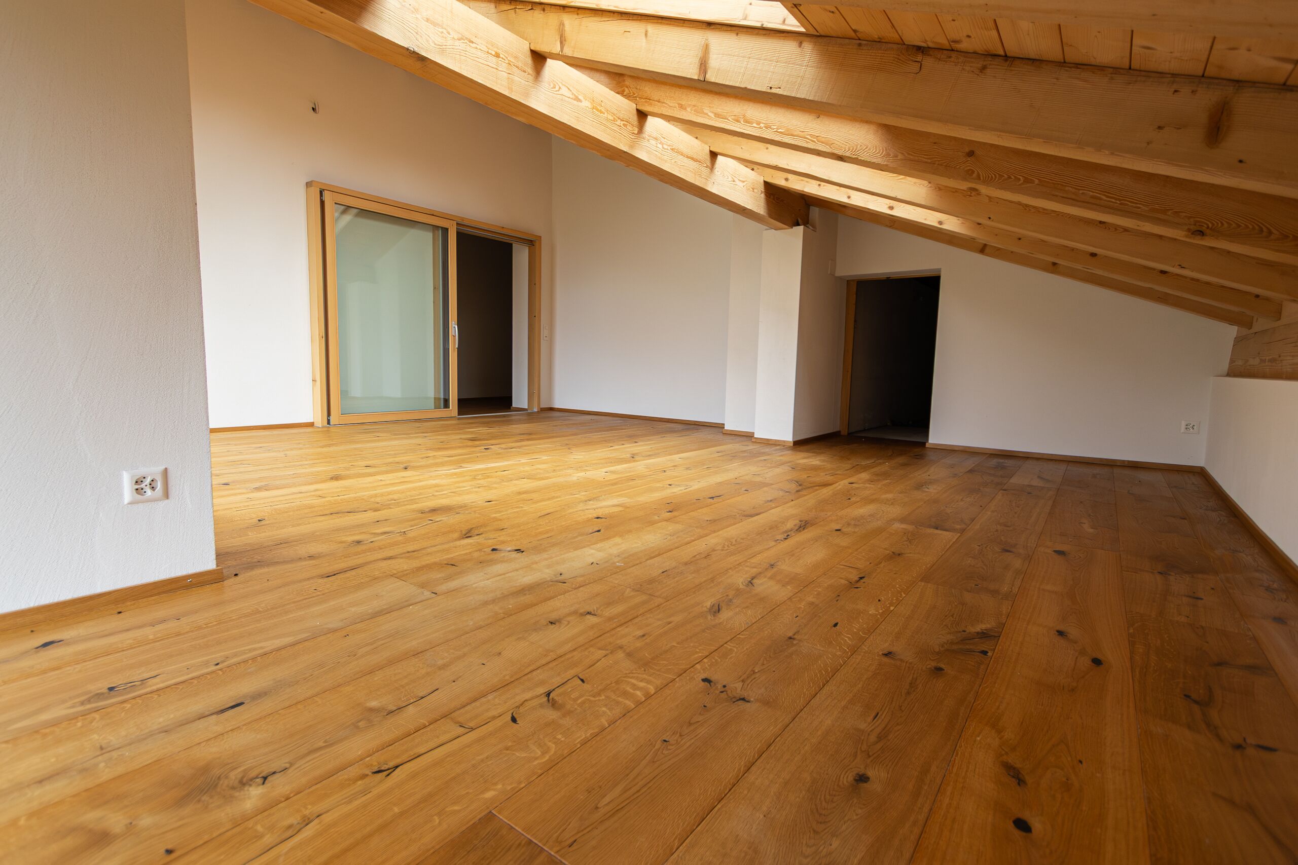 Dachgeschossraum mit Holzbalken und Holzboden