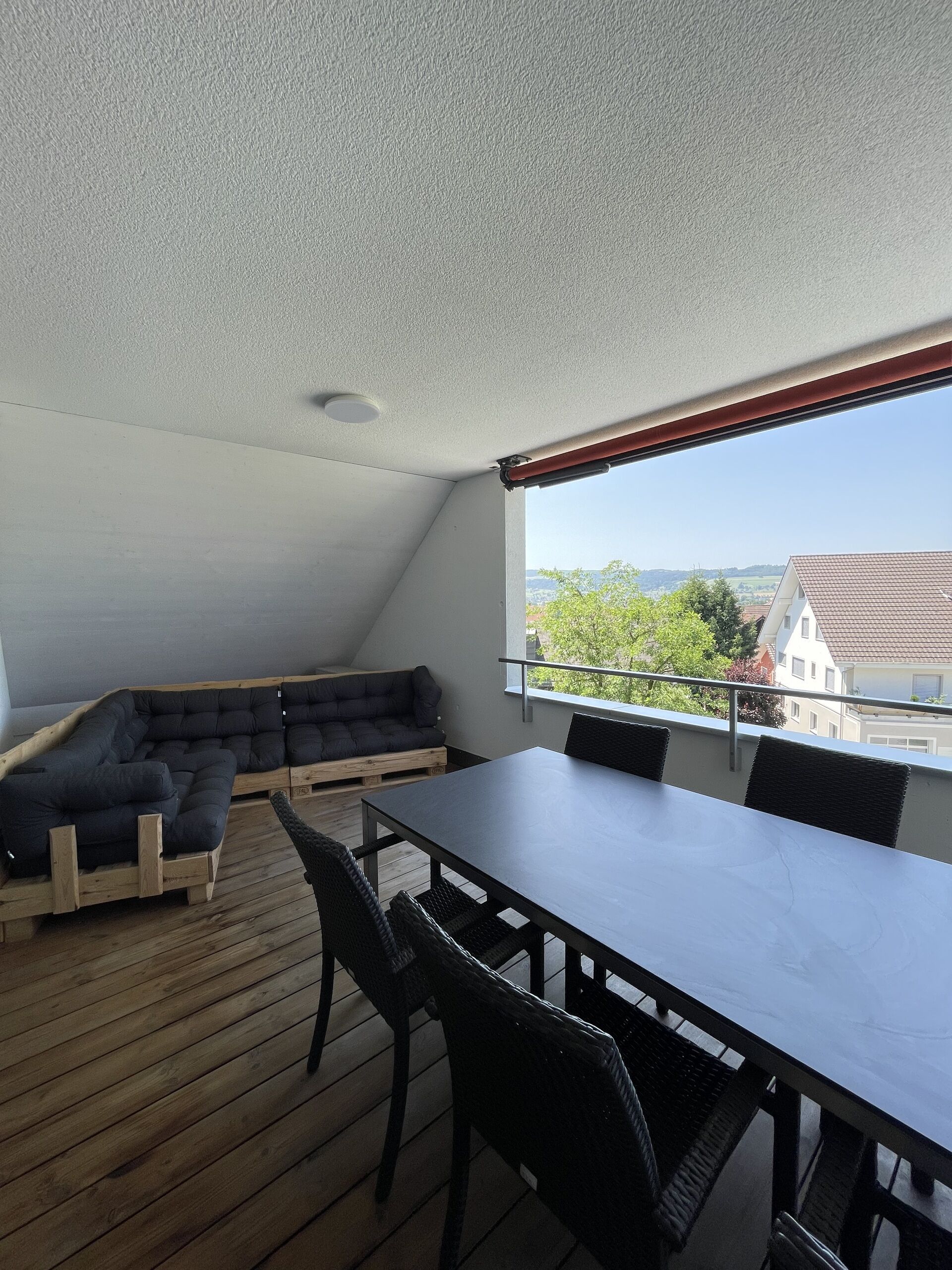 Überdachter Balkon mit Sitzgruppe und Esstisch