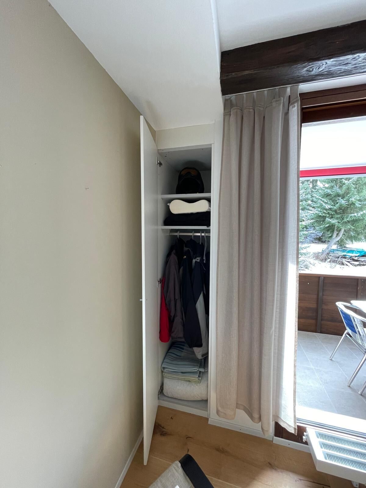 Schlafzimmer mit offenem Kleiderschrank und Balkonzugang