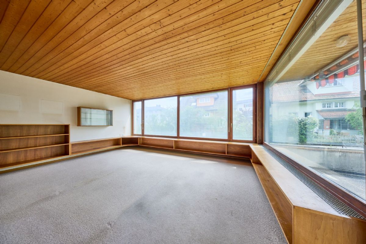 Großer Wohnraum mit Holzdecke und Panoramafenstern