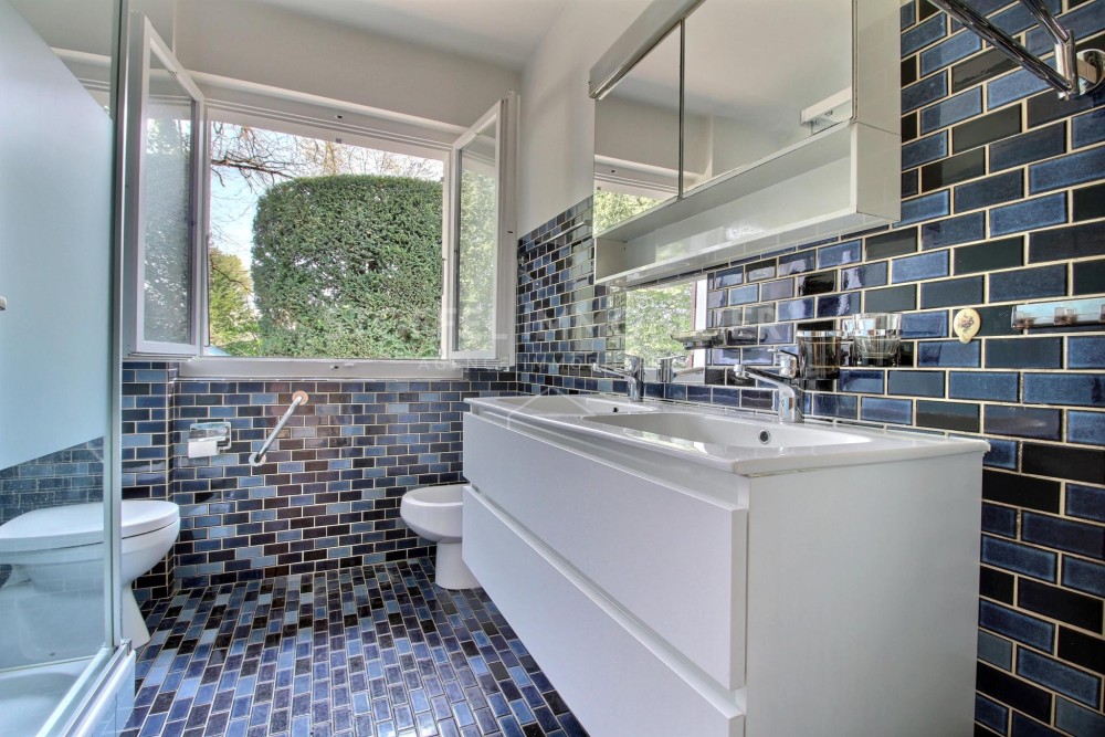 Badezimmer mit blauem Fliesenmuster und offenem Fenster