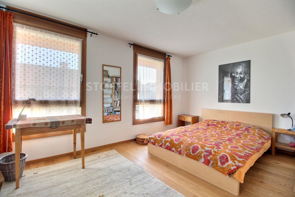 Helles Schlafzimmer mit Holzfenstern und Bett