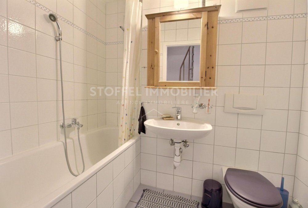 Kleines gefliestes Badezimmer mit Wanne und Spiegel