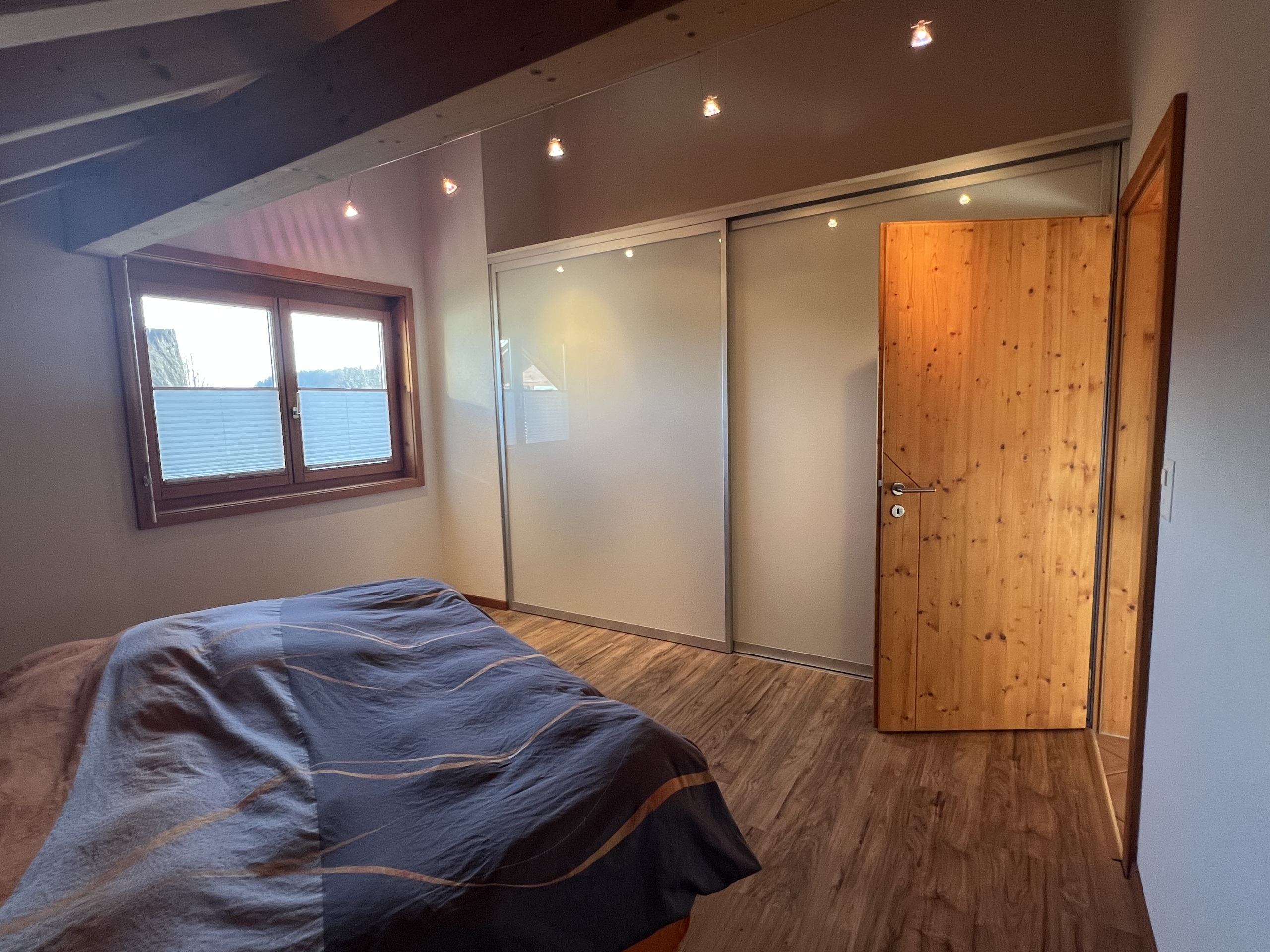 Schlafzimmer mit Holzdecke und Schiebetür