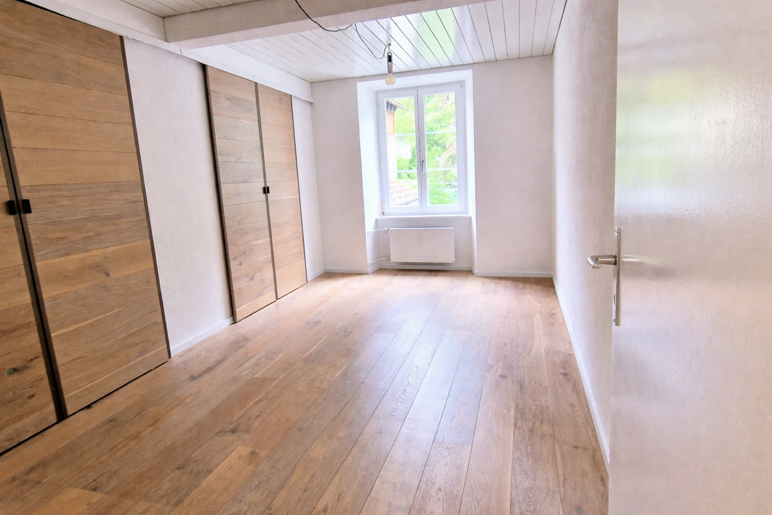Helles leeres Schlafzimmer mit Holzboden und Einbauschränken